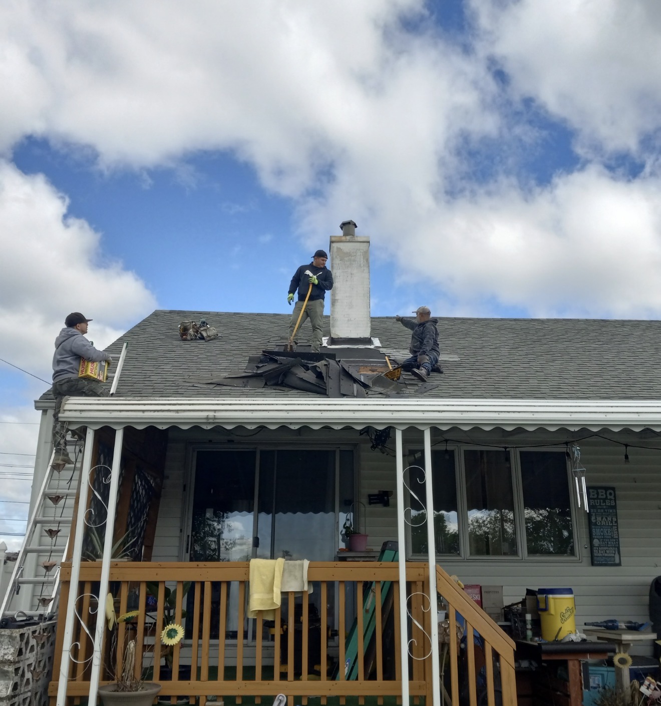 Crew removing shingles around a residential chimney