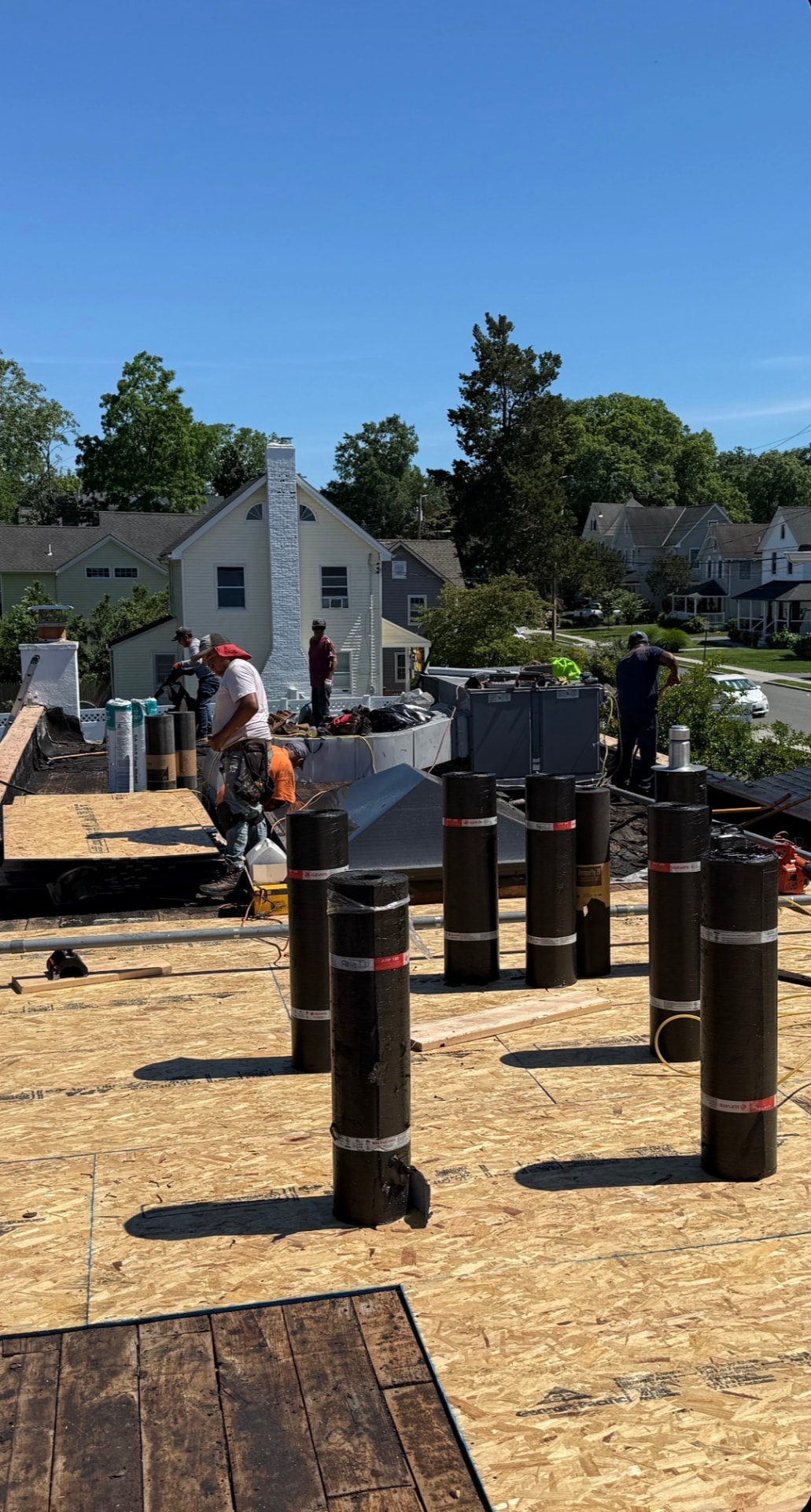 Commercial roofing crew preparing a wood roof deck for membrane installation