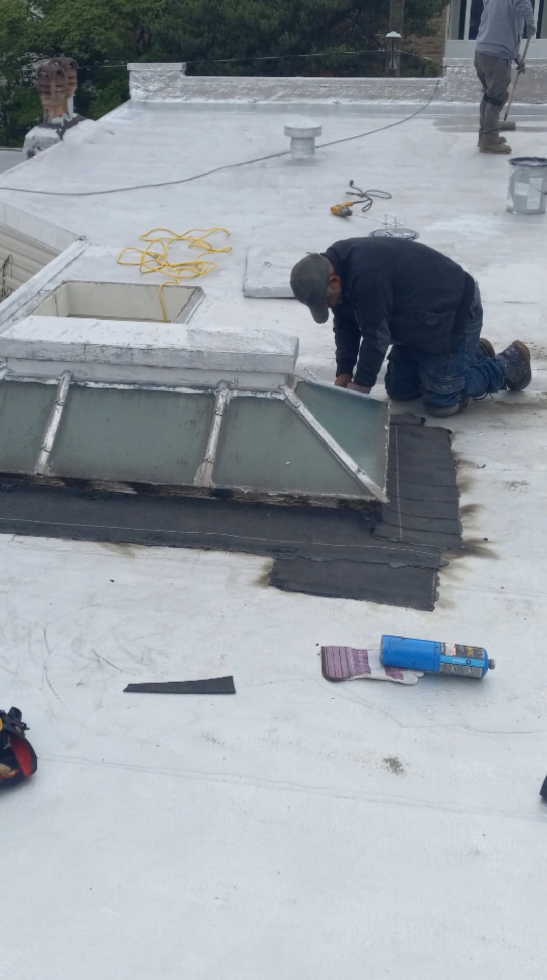 Roofing technician installing membrane around a skylight curb