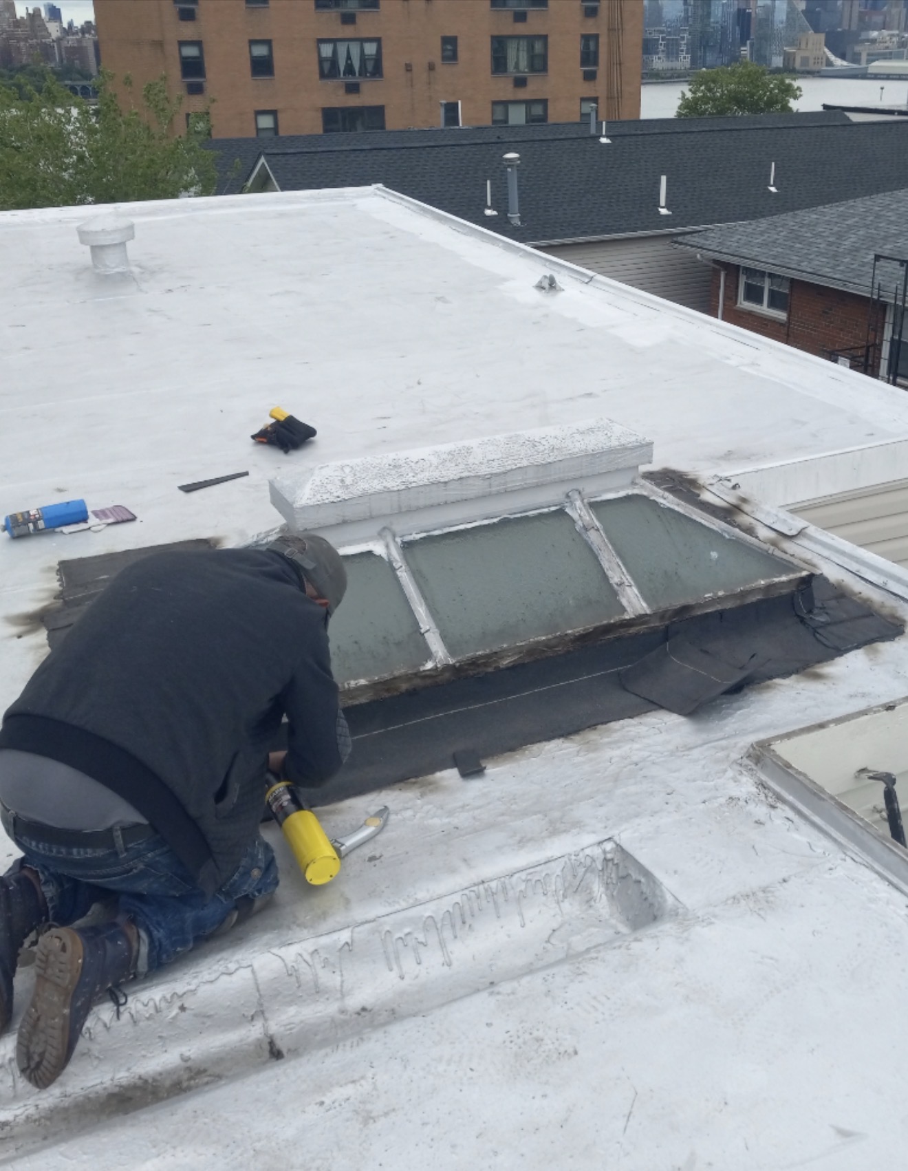 Roofer repairing flashing around a commercial roof skylight